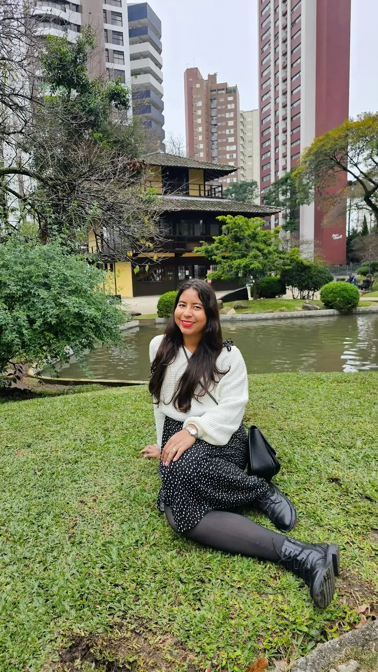 Pessoa sentada no gramado diante do lago e da Casa da Cultura