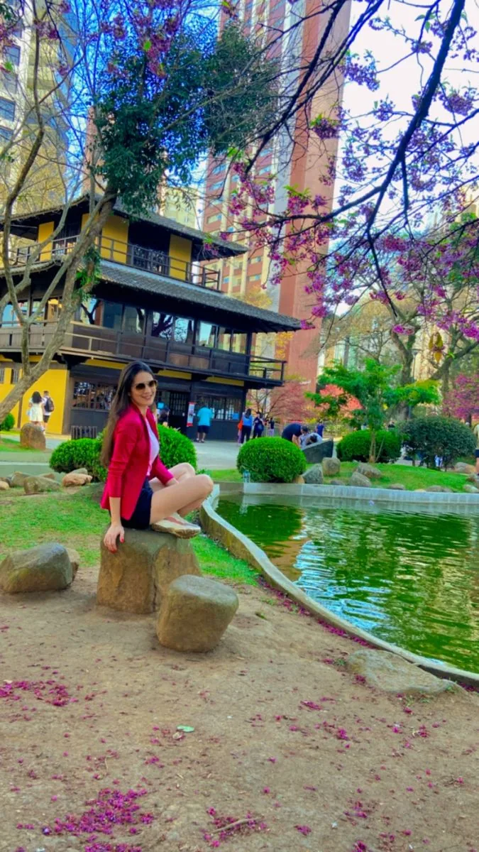Pessoa sentada junto ao lago e à Casa da Cultura da Praça do Japão