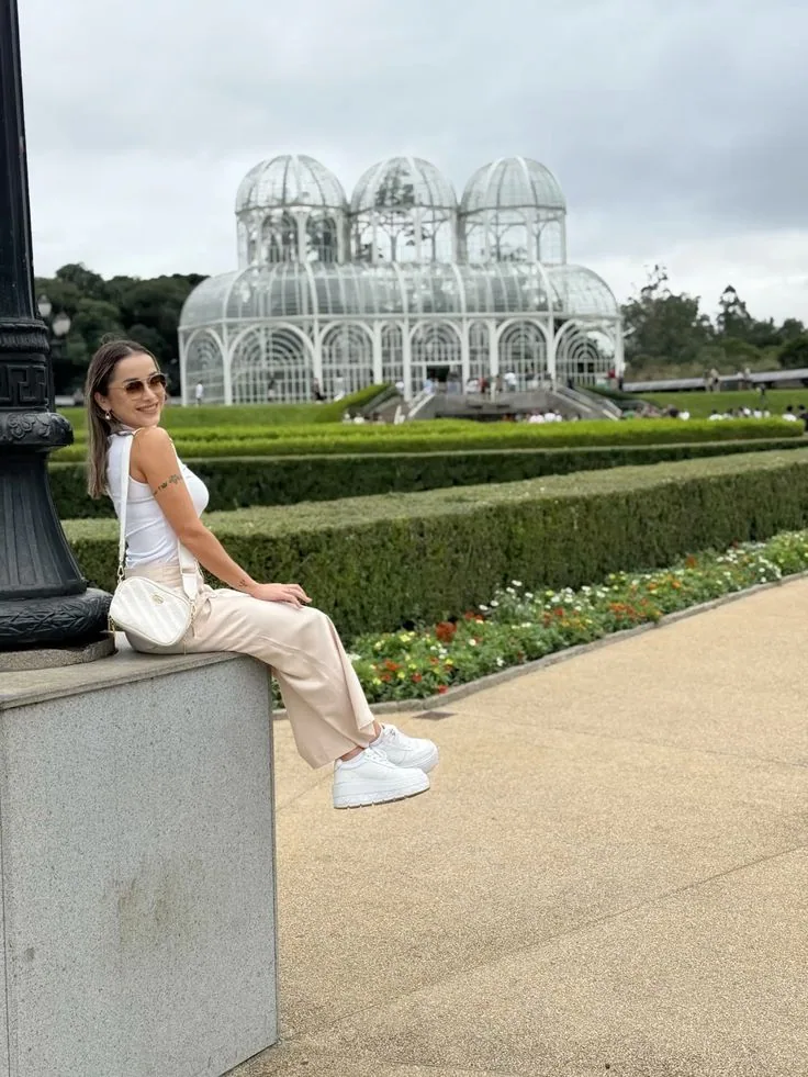 Pessoa sentada diante da estufa e dos jardins